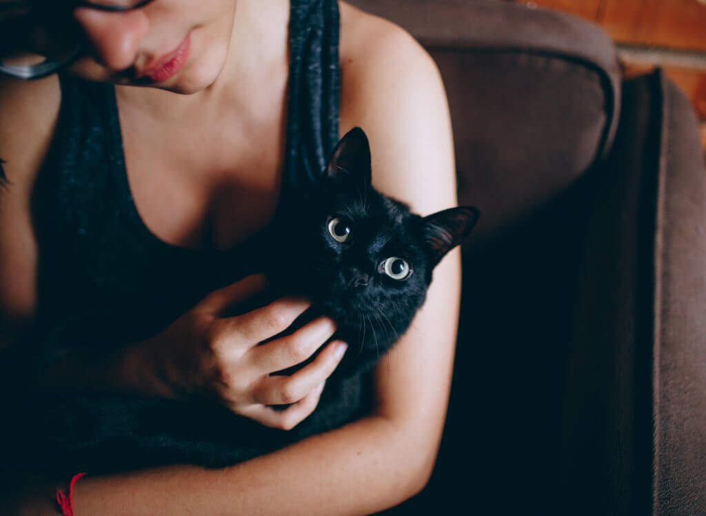 An image of a woman cuddling a black cat