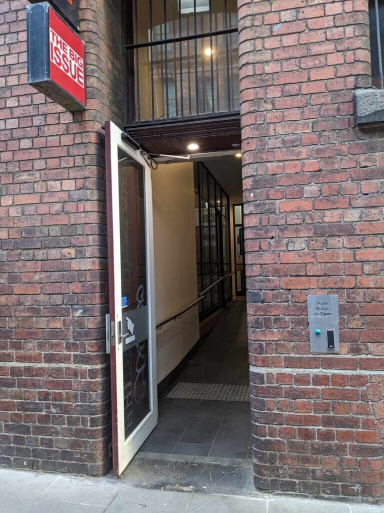 A door in a brick wall below a red and white 'the big issue' sign. 